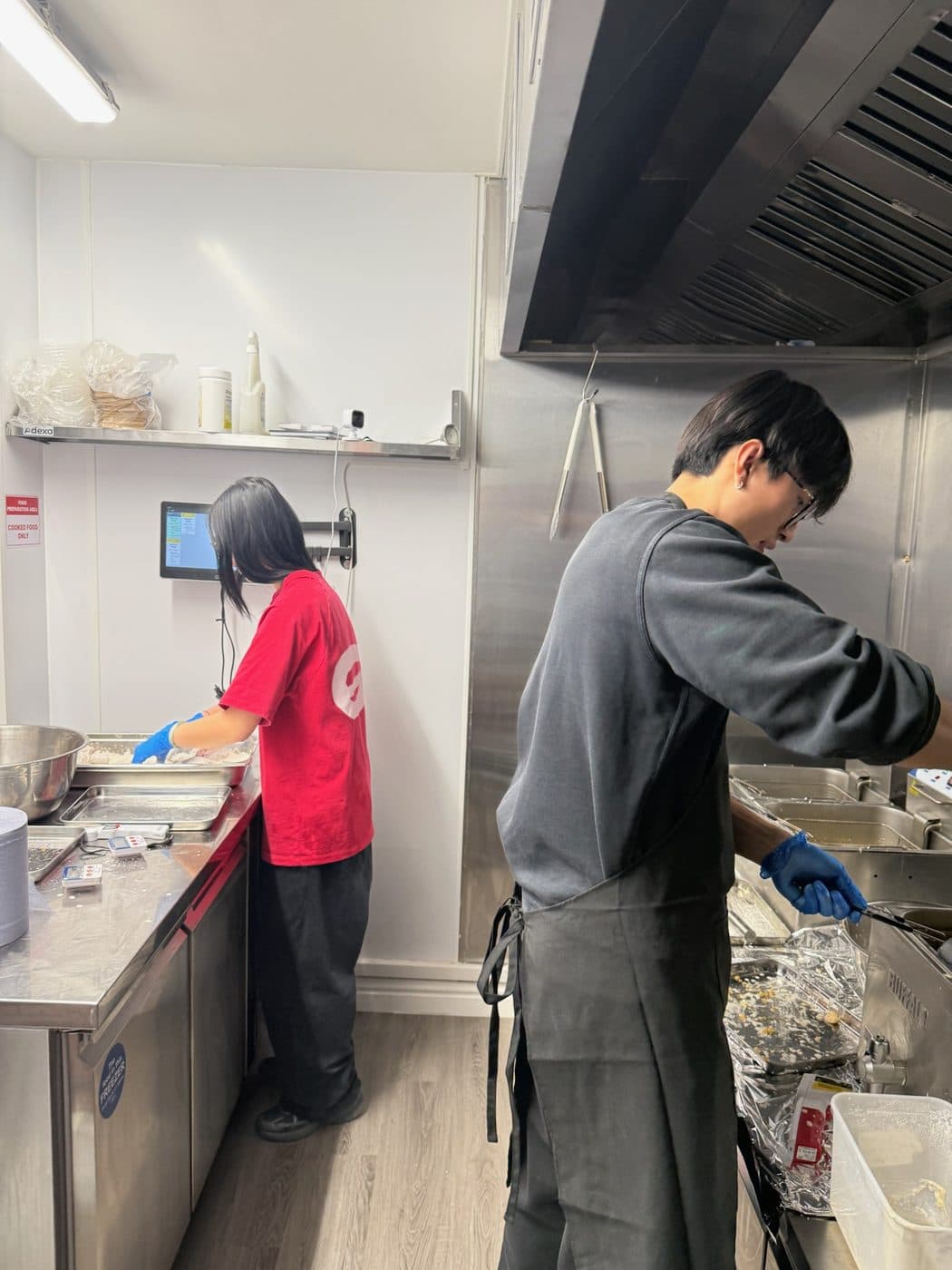 Chicken being dredged by hand in the INYUN kitchen, with the fryers alongside