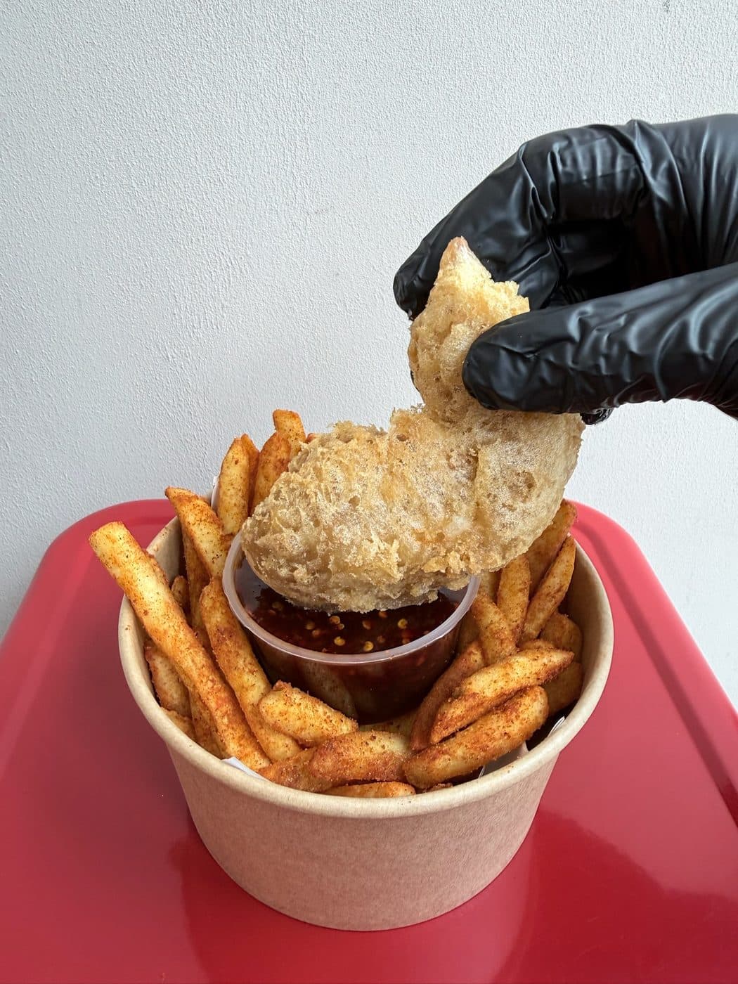 A piece of fried chicken dipped into INYUN's chilli sauce